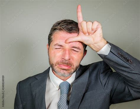 Unshaven Sad And Ashamed Businessman Crying Doing Loser Sign With Hand And Fingers On His