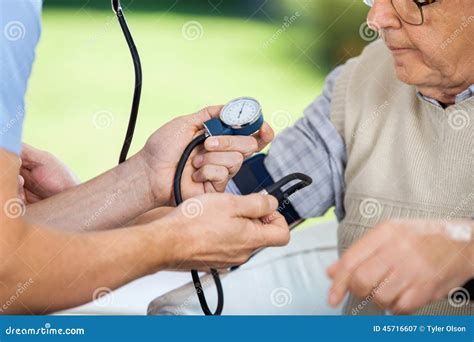 Male Caretaker Measuring Blood Pressure of Elderly Stock Image - Image of medical, outdoor: 45716607