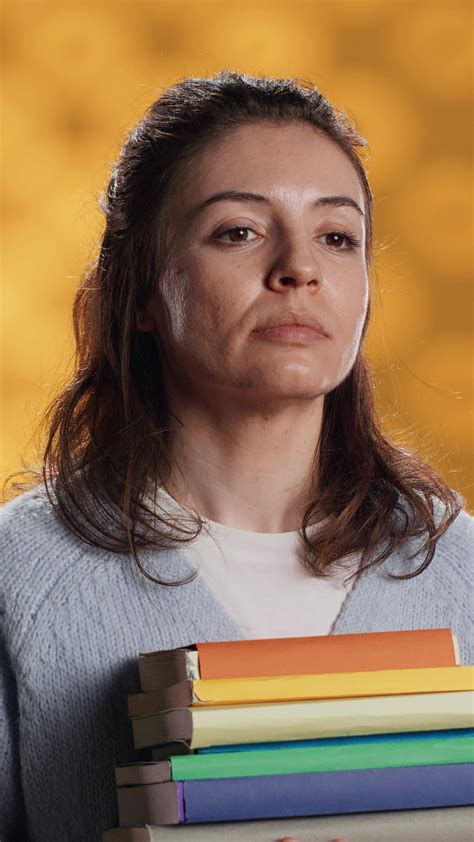 Vertical Portrait Of Upbeat Woman Holding Pile Of Books Enjoying