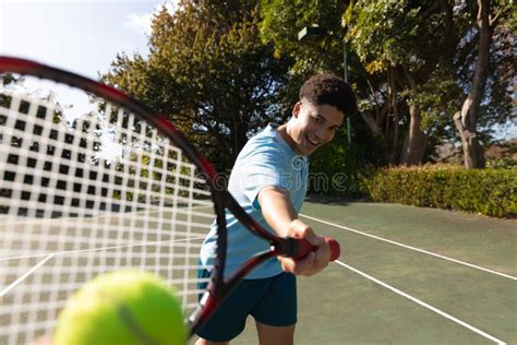 Biracial Man Playing Tennis Hitting Ball On Sunny Outdoor Tennis Court