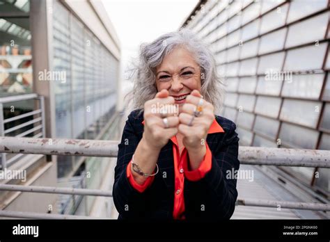 Happy Mature Businesswoman Showing Fists In Front Of Railing Stock