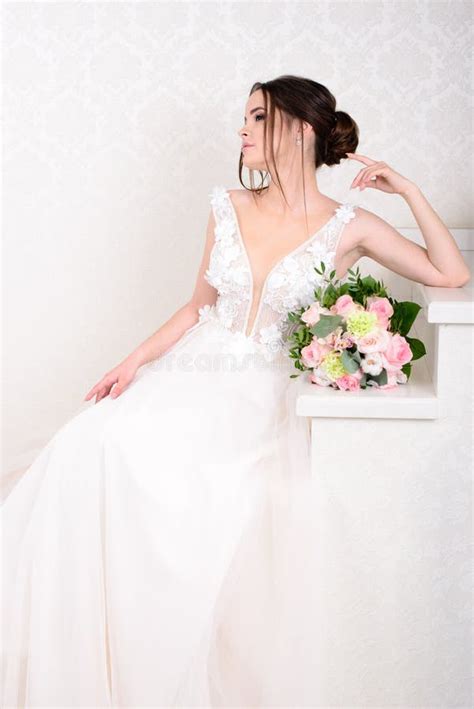 Slim Beautiful Woman Wearing Luxurious Wedding Dress Over White Studio