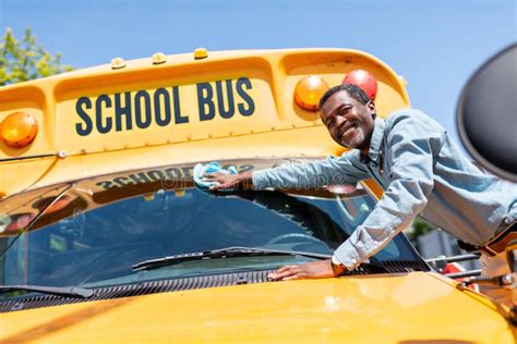 Smiling Mature African American Bus Driver Wiping Front Window Of