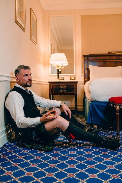 Premium Photo Handsome Mature Courageous Stylish Man Scotsman In Kilt Drinking Whiskey On The