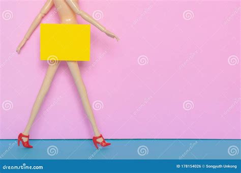 Naked Female Doll Walking With Red Shoe With Yellow Paper Hiding The Bottom Area Stock Photo