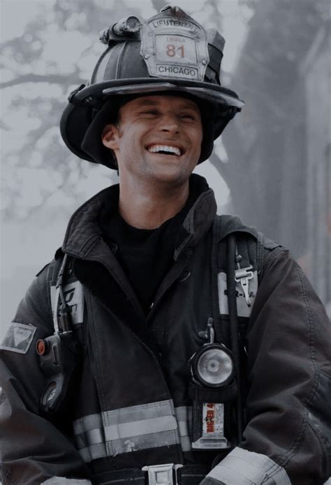 A Smiling Fireman Wearing A Helmet And Holding His Arms Crossed