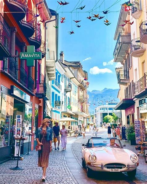 A Woman Is Walking Down The Street In Front Of A Car And Birds Flying