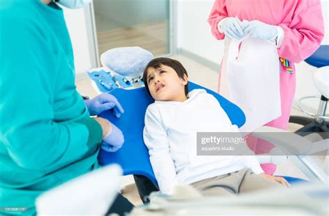 Pediatric Dentist With Nurse Treating Patient Teeth At The Dental