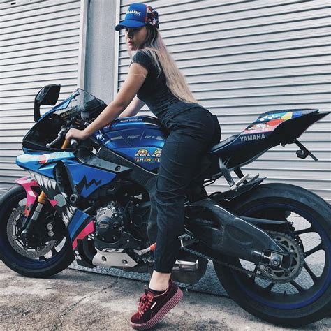 A Woman Sitting On Top Of A Blue Motorcycle Next To A Garage Door And