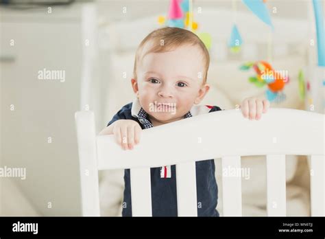 Toned Portrait Of Smiling 1 Year Old Baby Boy In Cot Looking In Camera