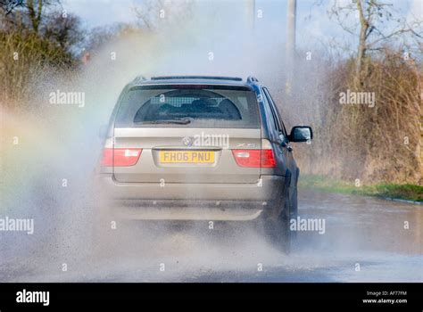 BMW X5 Car Driving Driving Through Flood On A Rural Road In England