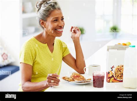 Mature Woman Eating Breakfast And Reading Newspaper Stock Photo Alamy