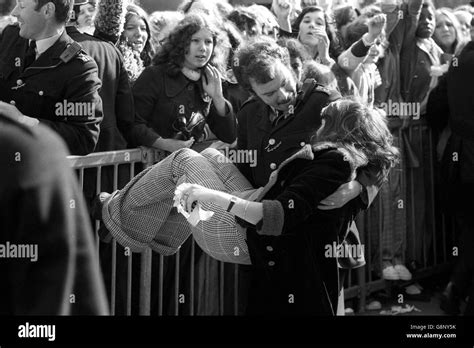 A Young Girl Who Fainted Is Carried From A Crowd Of Screaming Teenagers