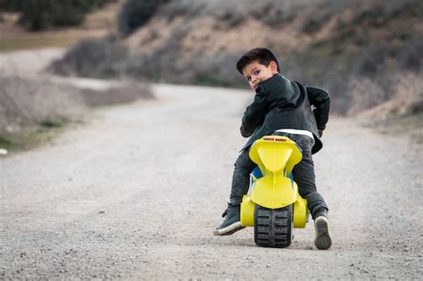 Un niño feliz conduciendo una motocicleta de juguete vestido con una