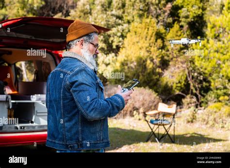 Side View Of Bearded Mature Male Operating Modern Flying Drone With