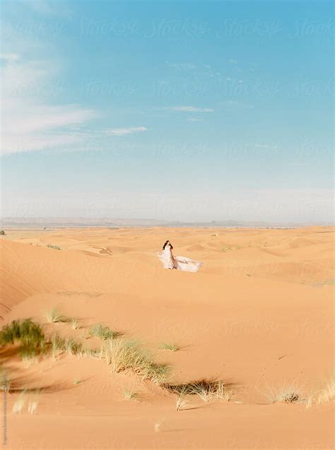 A Long Haired Brunette Woman Walking In The Desert In A Airy Wavy Pink Dress By Stocksy