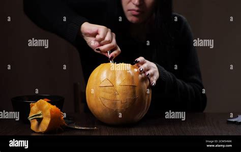 Young Brunette Woman Carves A Pumpkin For Halloween Preparation Stock