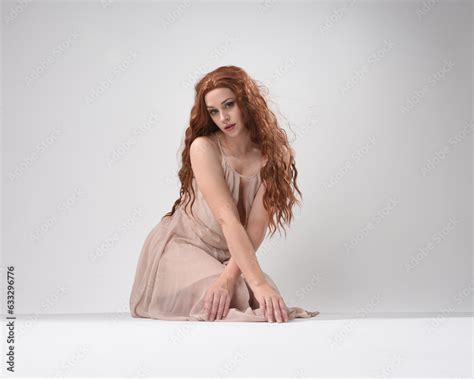 Full Length Portrait Of Beautiful Brunette Model Wearing A Pink Dress Graceful Sitting Pose