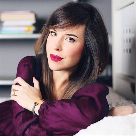 A Woman Laying On Top Of A Bed With Her Arms Crossed And Looking Off To