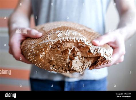 Holds An Object In His Hand Packed In Brown Paper With Holes Mesh