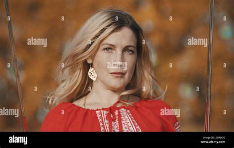 Blonde Woman In Red National Costume In Autumn Forest Holding Swords