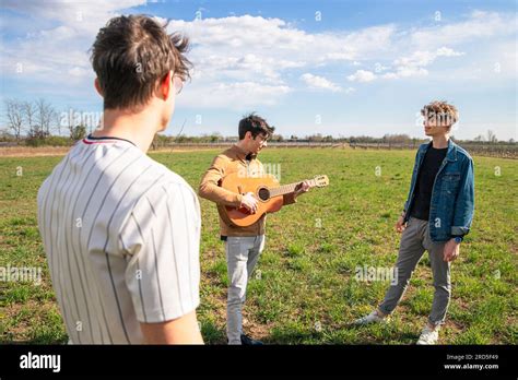 A Group Of Friends Meet In A Field To Play Guitar And Sing Together