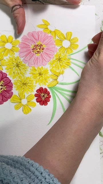 someone is drawing flowers on paper with colored pencils