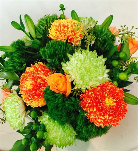 An Arrangement Of Flowers In A Vase On A White Table Top With Green