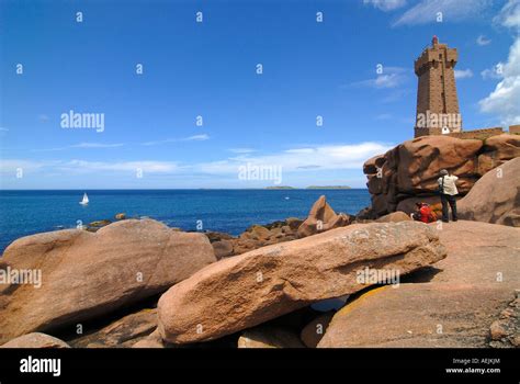 Couple Taking Pictures Of A Lighthouse At The Cote De Granit Rose