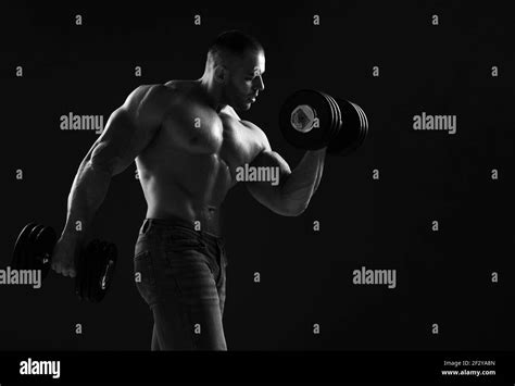 Muscular Men Weightlifter Is Working Out In Gym Lifting Alternately Two Big Heavy Dumbbells