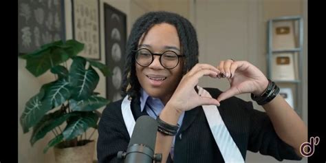 a woman with glasses making a heart sign while sitting in front of a ...