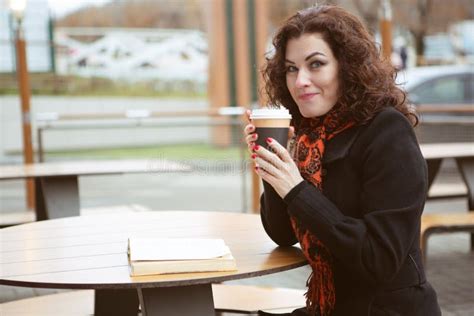 A Pretty Woman Slyly Looks At The Camera Holding A Glass Of Hot Strong Coffee Stock Image