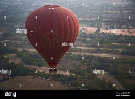 A Single Red Hot Air Balloon Flies Over A Forest Of Trees At Sunrise In Bagan Myanmar Burma