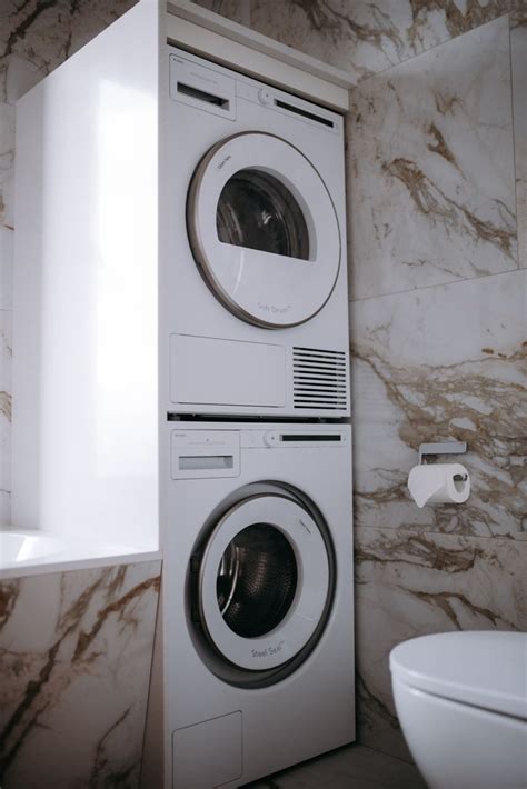 A Washer And Dryer Stacked On Top Of Each Other Next To A Toilet