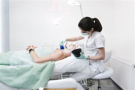 The Female Dermatologist Examining Face Of Young Patient With