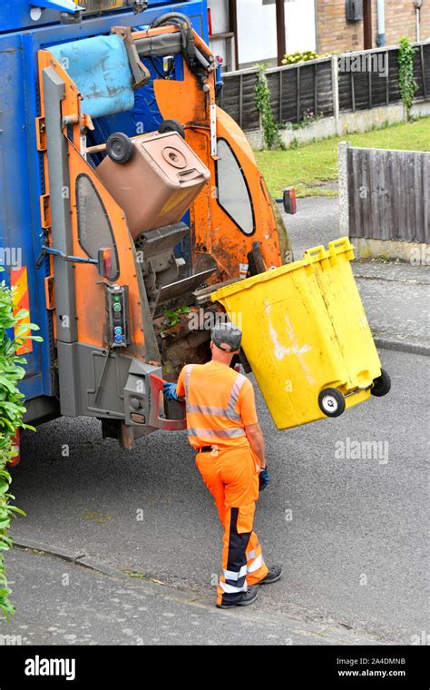 Refuse Collection Wearing High Vis Clothes Operates Lifting Up Controls