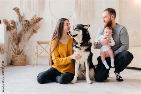 Family with baby boy sitting on the bed with cute dog. Mother and ...