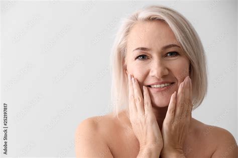 Mature Woman Giving Herself Face Massage On Light Background Stock Photo Adobe Stock
