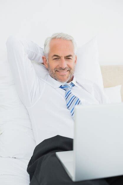 Premium Photo Mature Businessman Looking At Laptop In Bed