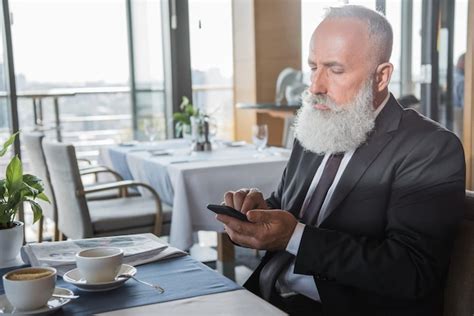 Premium Photo Mature Bearded Businessman Using Smartphone In