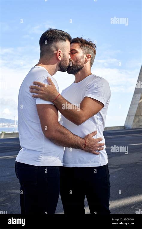 Una pareja gay cariñosa besando en el puente contra el cielo Fotografía