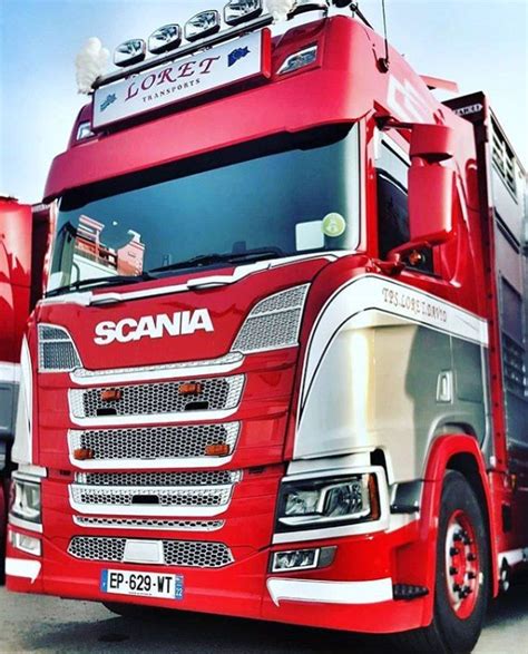 A Red Scania Truck Parked In A Parking Lot Next To Other Trucks And