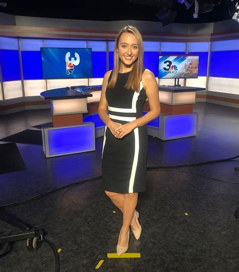 A Woman In A Black And White Dress Is Standing On The Set Of Tv News