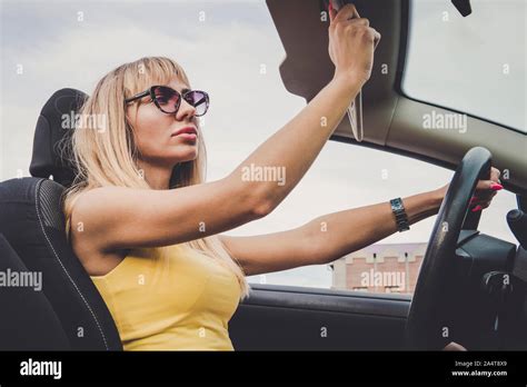 Une femme admire sa beauté dans la réflexion Young cheerful woman driving car Fille blonde