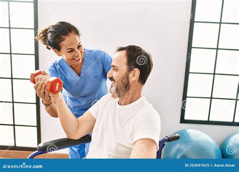 Middle Age Man And Woman Having Rehab Session Using Dumbbell Sitting On Wheelchair At