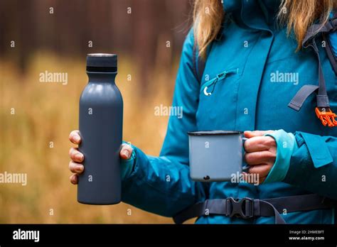 Female Hiker Holding Thermos With Hot Drink And Travel Mug In Forest Woman Hiking And Camping