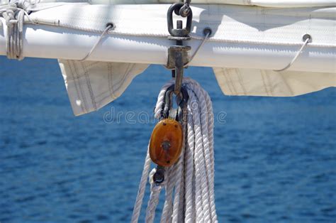 Vela Del Velero Y Cuerdas De Madera Del Aparejo Contra Fondo Del Agua