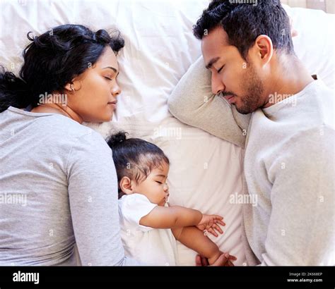 Young family sleeping together from above. Two parents sleeping with their baby girl. Little ...