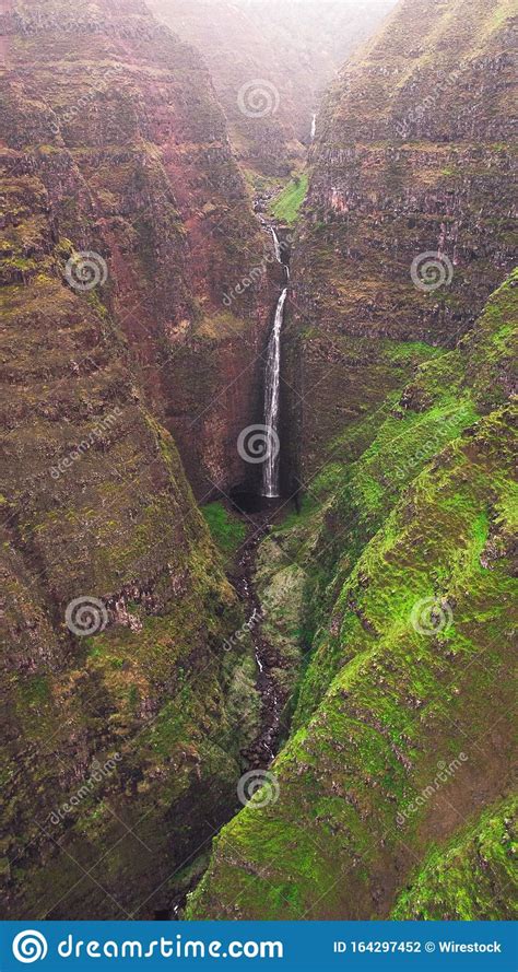 Vertical Shot Of A Waterfall Among The Mountains Captured In Kauai