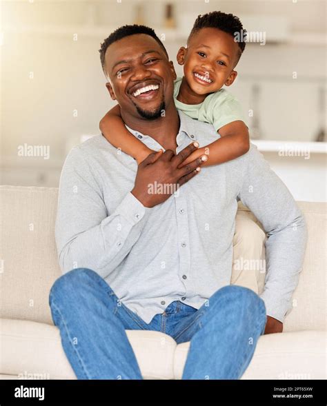 Portrait of an affectionate black man holding his child on a couch. African american father ...